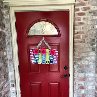 A vibrant red door adorned with a cheerful welcome sign, inviting guests into a cozy home.