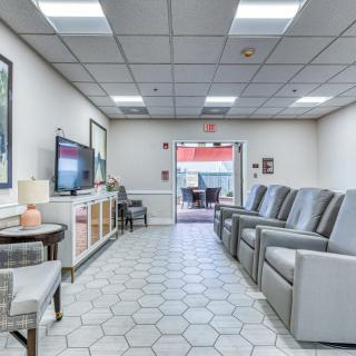 A spacious waiting room with comfortable seating and a television.