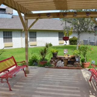 A cozy patio with a pergola overlooking a garden and benches.