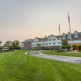 A large hotel with a well-maintained lawn and driveway, featuring flags at the entrance.