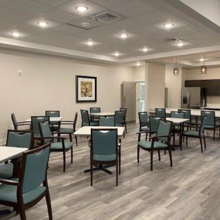 A modern and spacious dining room with multiple tables and chairs, well-lit and featuring elegant flooring.