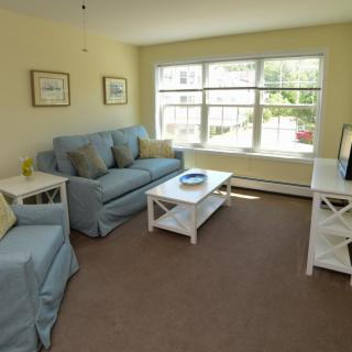 A cozy living room with blue sofas and a large window letting in natural light.