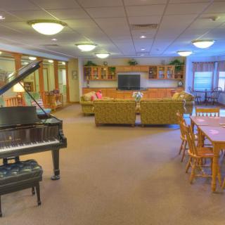 A cozy living room with a piano, seating area, and dining table.