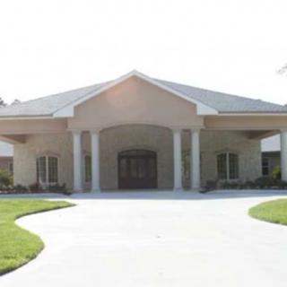 A symmetrical building entrance with columns and a peaked roof.