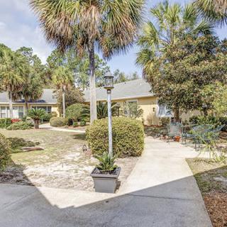 A scenic view of a residential garden with a walkway lined with palm trees.
