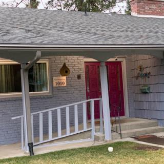 A cozy house with a porch featuring a red door and an accessibility ramp.