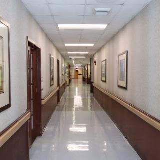 A well-lit hallway with framed artwork and polished floors.