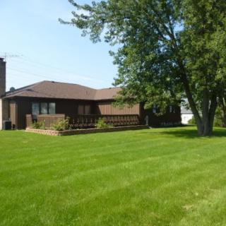 A suburban house with a well-maintained lawn and surrounding trees.