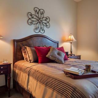 A cozy and well-decorated bedroom with a wooden bed, pillows, and ambient lighting.