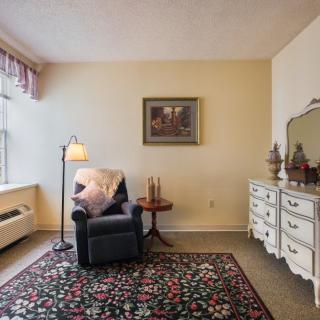 Cozy living room corner with an armchair, small table, and dresser.