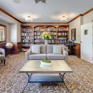 A cozy living room with a sofa, coffee table, and bookshelves lining the walls.