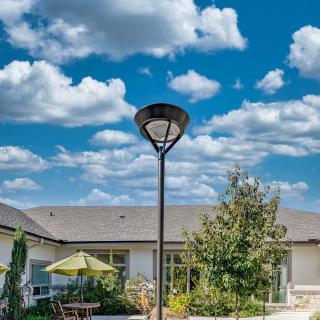 A sunny outdoor patio with a lamp post and a building in the background under a vibrant sky.