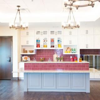 A modern kitchen with a central island, white cabinets, and colorful tile backsplash.