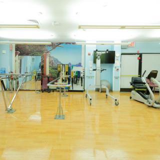 A well-equipped gym featuring various fitness machines and a mirrored wall.