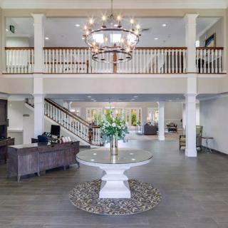A spacious hotel lobby featuring a grand chandelier, elegant staircase, and stylish reception area.