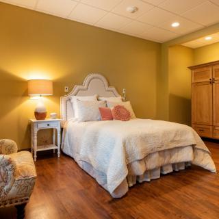 A cozy bedroom with a comfortable bed, warm lighting, and elegant wooden furniture.