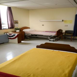 An empty hospital room with two beds and minimal furnishings.