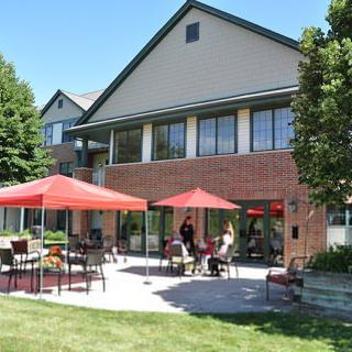 People enjoying a sunny day on a patio with red umbrellas.