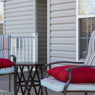 A cozy outdoor seating area featuring striped chairs with red cushions and a small table, perfect for relaxation.