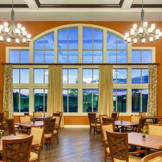 A spacious dining area featuring large arched windows and elegant chandeliers.