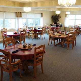 A well-lit dining area with multiple round tables and chairs.