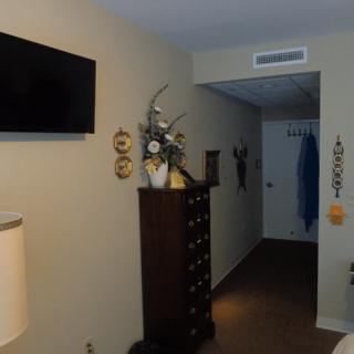 A hallway with a dresser, wall-mounted television, and decorative items.