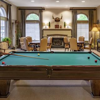 A cozy game room featuring a billiard table and seating area by the fireplace.