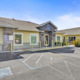 A small commercial building with a parking lot and entrance, captured during the daytime.