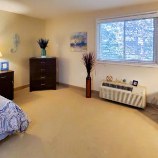 A cozy bedroom with a bed, dresser, and window view.