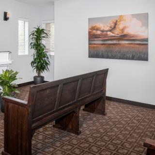 A tranquil waiting area featuring a wooden bench, decorative plants, and an artistic landscape painting.