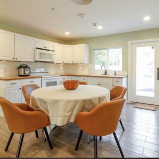 A modern kitchen with a cozy dining area featuring a round table and orange chairs.