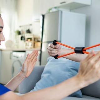 Two people playing with an orange slingshot toy indoors.