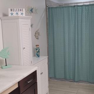 A neatly arranged bathroom featuring a teal shower curtain and white cabinetry.