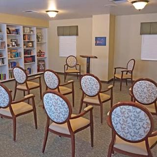 A small room with chairs arranged in rows, a podium, and bookshelves along the wall.
