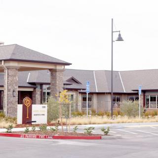 A commercial building with a landscaped entrance and adjacent parking area.