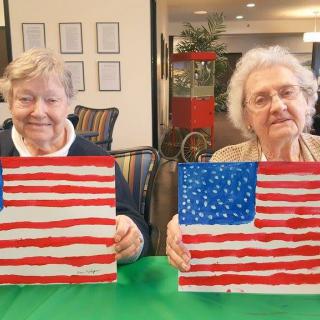 Two seniors proudly display their American flag paintings.