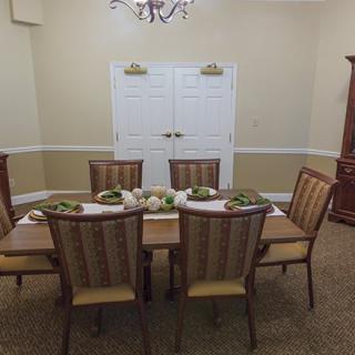 A well-decorated dining room with a table set for a meal and elegant chairs around it.