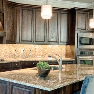 A modern kitchen featuring rich wood cabinetry and elegant granite countertops, illuminated by stylish pendant lights.