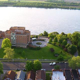 Aerial view of a building surrounded by greenery next to a river.