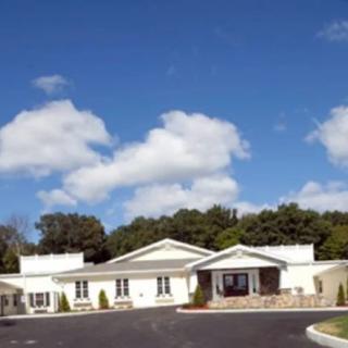 An exterior view of a building under a blue sky with scattered clouds.