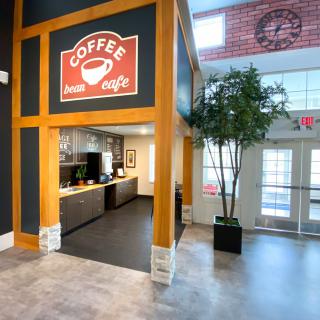 A modern and cozy coffee shop interior with a prominent coffee sign and indoor plant.