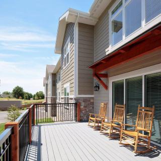 A modern residential building with a spacious balcony featuring wooden rocking chairs.