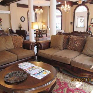 A luxurious living room featuring elegant sofas, a round coffee table, chandeliers, and decorative pillars.