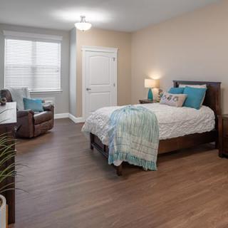 A cozy and neatly decorated bedroom with wooden flooring and stylish furniture.