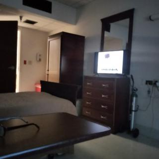 A hospital room with a bed, television, and furniture.