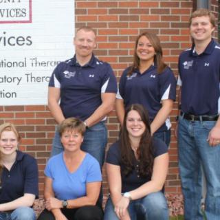 A group of healthcare professionals posing in front of a brick wall.