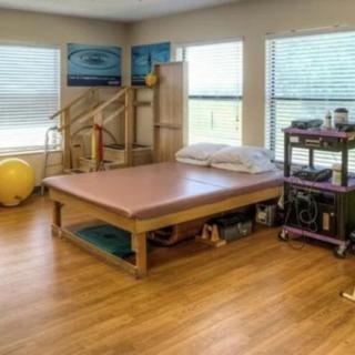 A well-equipped physical therapy room with a treatment table and various exercise equipment.
