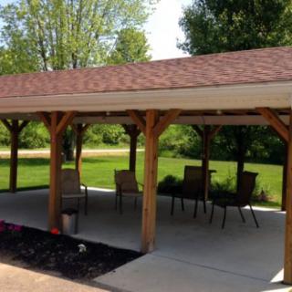 A wooden pavilion with patio furniture set in a garden.