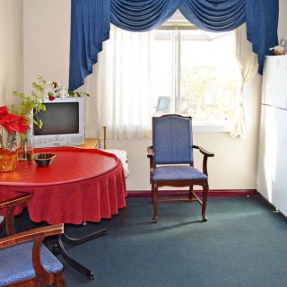 A cozy living room with a red tablecloth, blue curtains, and classic furniture.