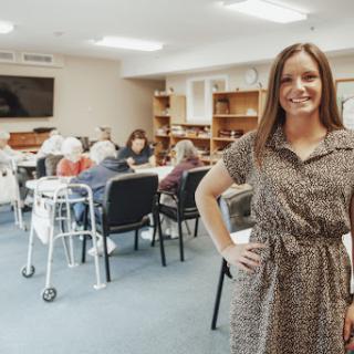 A dedicated caregiver engaging with the elderly in a warm communal environment.